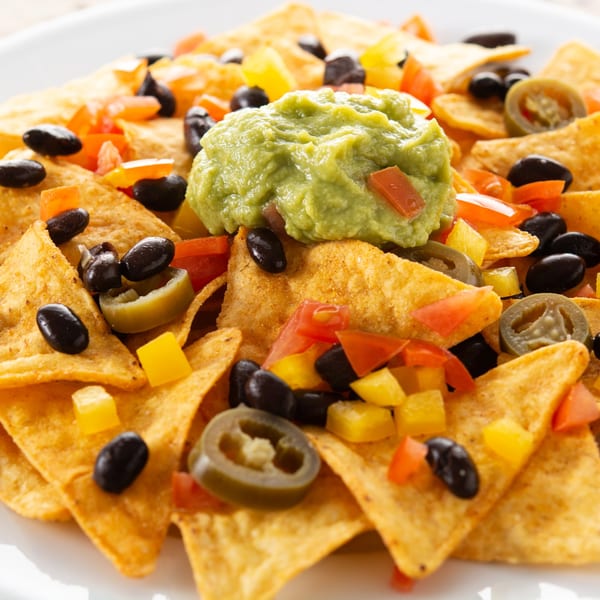 Close-up of Vallarta Tequila Bar's nachos with guacamole, black beans, jalapeños, and diced peppers.