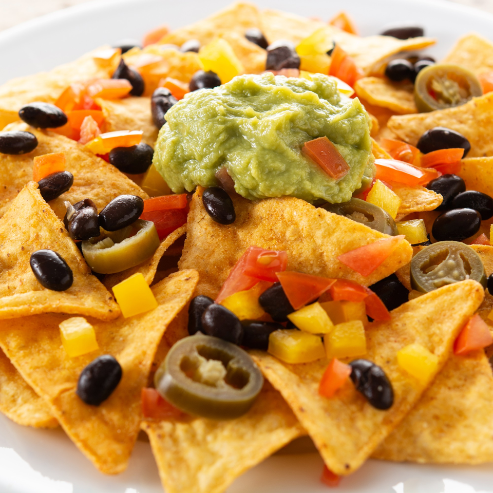 Close-up of Vallarta Tequila Bar's nachos with guacamole, black beans, jalapeños, and diced peppers.